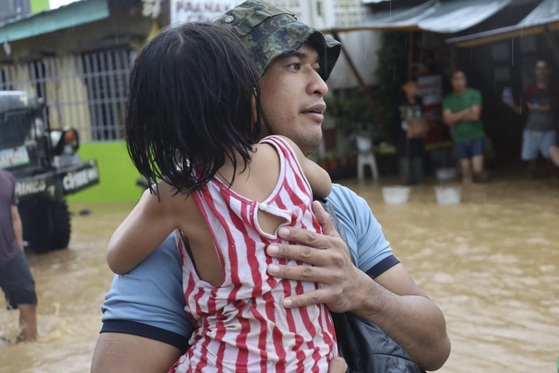 28일 태풍 '날개'의 영향을 홍수 피해가 발생한 필리핀 남부 민다나오섬 파랑에서 한 남성이 어린 여자아이를 구조해 안전한 장소로 이동하고 있다. 필리핀 해안구조대 제공·AP=연합뉴스