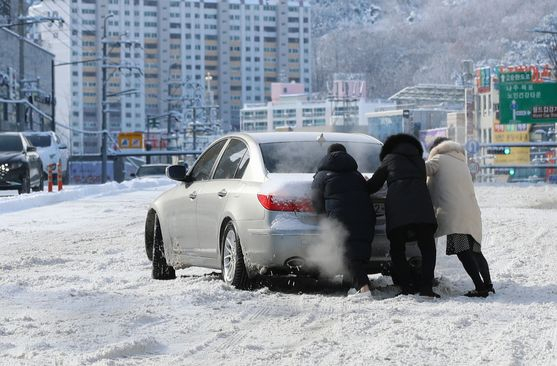 이날 광주시 남구의 한 도로에서 시민들이 차량의 탈출을 돕는 모습. [연합뉴스]