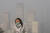 2021년 11월 스모그로 인해 하늘이 짙은 회색으로 변한 중국 베이징 중앙 업무 지구의 사무실 건물 사이를 안면 마스크를 착용한 한 여성이  걸어가고 있다. AP=연합뉴스