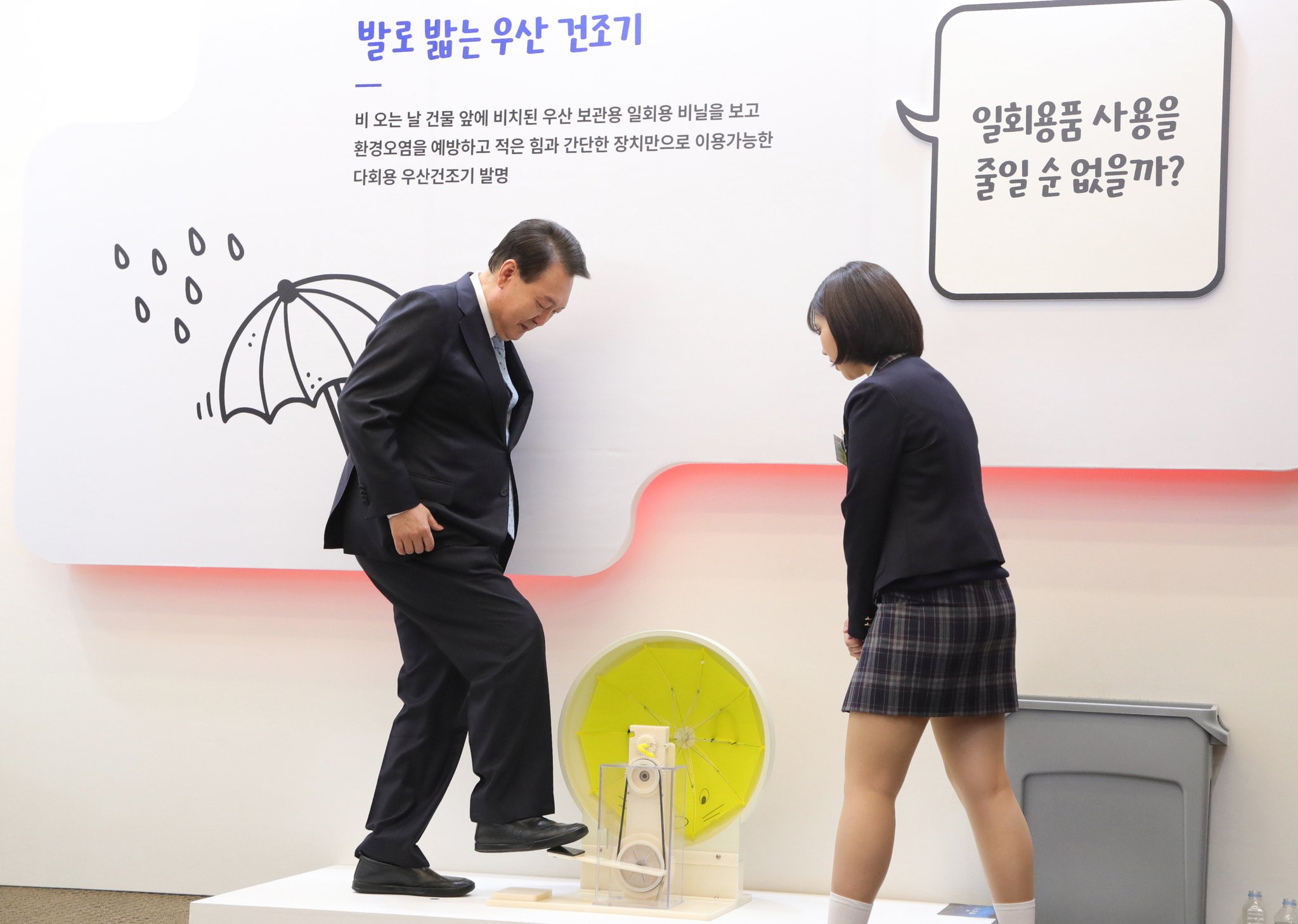 윤석열 대통령이 청소년 발명 전시회장을 찾아 '발로 밟는 우산 건조기'를 시연하고 있다. 뉴시스