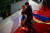 프랑스 남부 휴양도시 칸에서 열린 제76회 칸 국제영화제에 깔린 레드카펫 위에서 우크라이나 국기를 떠올리게 하는 드레스를 입은 여성이 지난 21일(현지시간) 가짜 피를 자신의 몸에 뿌린 뒤 보안 요원에게 제지당하고 있다. AFP=연합뉴스