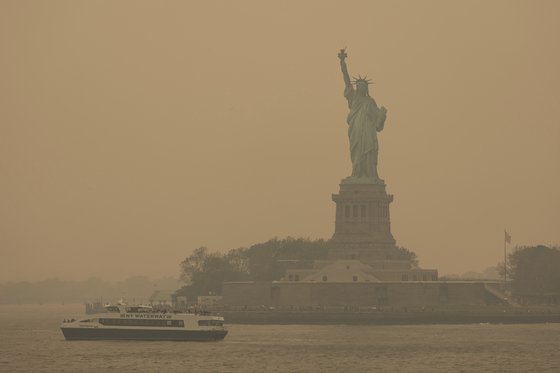 캐나다 산불로 인해 발생한 연기가 미국까지 넘어와 하늘을 탁한 오렌지색으로 물들이는 등 공기질을 악화시켰다. 7일(현지시간) 뉴욕의 상징물인 '자유의 여신상'도 형체를 겨우 알아볼 정도다. AP=연합뉴스