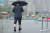 장맛비가 굵어진 29일 오전 양복 차림의 한 남성이 바지를 걷어 올린 채 광화문광장을 걸어가고 있다. 연합뉴스