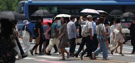 지난 21일 전국적으로 무더운 날씨가 이어진 가운데 시민들이 서울 광화문사거리에서 우산과 양산을 쓴 채 횡단보도를 건너고 있다. 연합뉴스