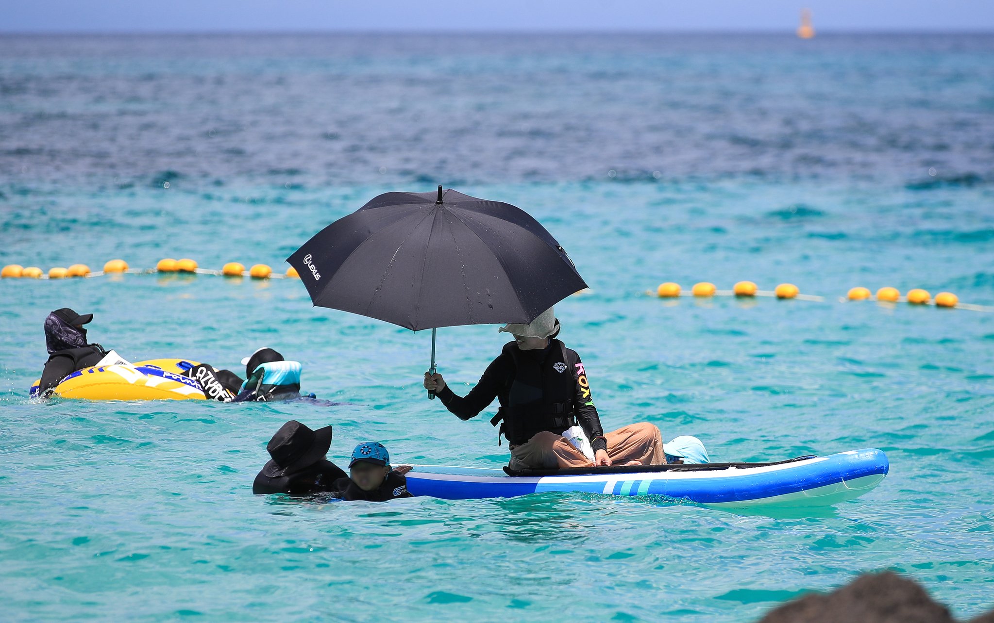 제주시 한경면 판포포구를 찾은 한 피서객이 우산을 들고 물놀이를 즐기고 있다. 뉴시스