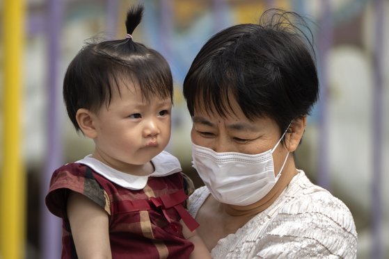 중국에서 한 여성이 마스크를 쓴 채 아이를 안고 있다. AP=연합뉴스