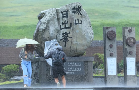 제6호 태풍 카눈이 한반도를 향해 접근 중인 9일 오후 제주 서귀포시 성산일출봉을 찾은 관광객들이 강한 비바람을 맞고 있다. 연합뉴스