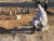 15일(현지시간) 리비아 데르나에서 대홍수 희생자의 무덤 앞에 마스크를 쓰고 앉아 있는 사람. AP=연합뉴스