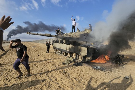 7일(현지시간) 이스라엘이 팔레스타인 무장정파 하마스로부터 공격 받은 가운데, 팔레스타인인들이 가자 지구 인근에서 불타는 탱크 위에서 환호하고 있다. AP=연합뉴스