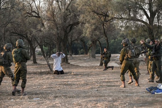 12일(현지시간) 이스라엘 군인들이 지난 7일 음악 축제 기간 동안 하마스 무장세력에 의해 참가자 270명이 살해된 키부츠 비에리 인근에서 순찰 중 한 남자를 체포하고 잌ㅅ다.AFP=연합뉴스 