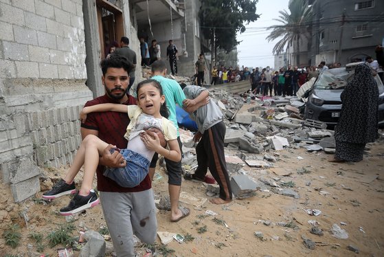 29일(현지시간) 가자 지구 남부 라파 주택가에 대한 이스라엘의 폭격 이후 팔레스타인인이 소녀를 안고 대피하고 있다. UPI=연합뉴스