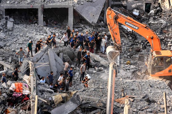 25일(현지시간) 가자지구 남부 칸 유니스에서 이스라엘의 폭격으로 파괴된 건물들 사이에서 생존자와 희생자들의 시신을 수색하는 동안 굴착기가 잔해를 치우고 있다. AFP=연합뉴스