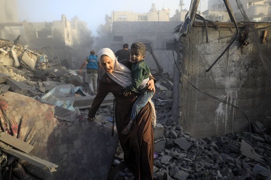 6일(현지시간) 이스라엘의 공습으로 파괴된 가자지구 중앙 알마가지 난민 캠프 인근에서 주민들이 대피하고 있다. AFP=연합뉴스