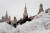 지난달 27일(현지시간) 모스크바에 폭설이 내린 후 크렘린궁 스파스카야 타워 앞 붉은 광장의 눈 언덕을 사람들이 지나가고 있다. EPA=연합뉴스