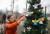 우크라이나 여성이 지난 22일 우크라이나 수도 키이우의 독립광장 인근에 놓인 크리스마스 트리를 장식하고 있다. EPA=연합뉴스