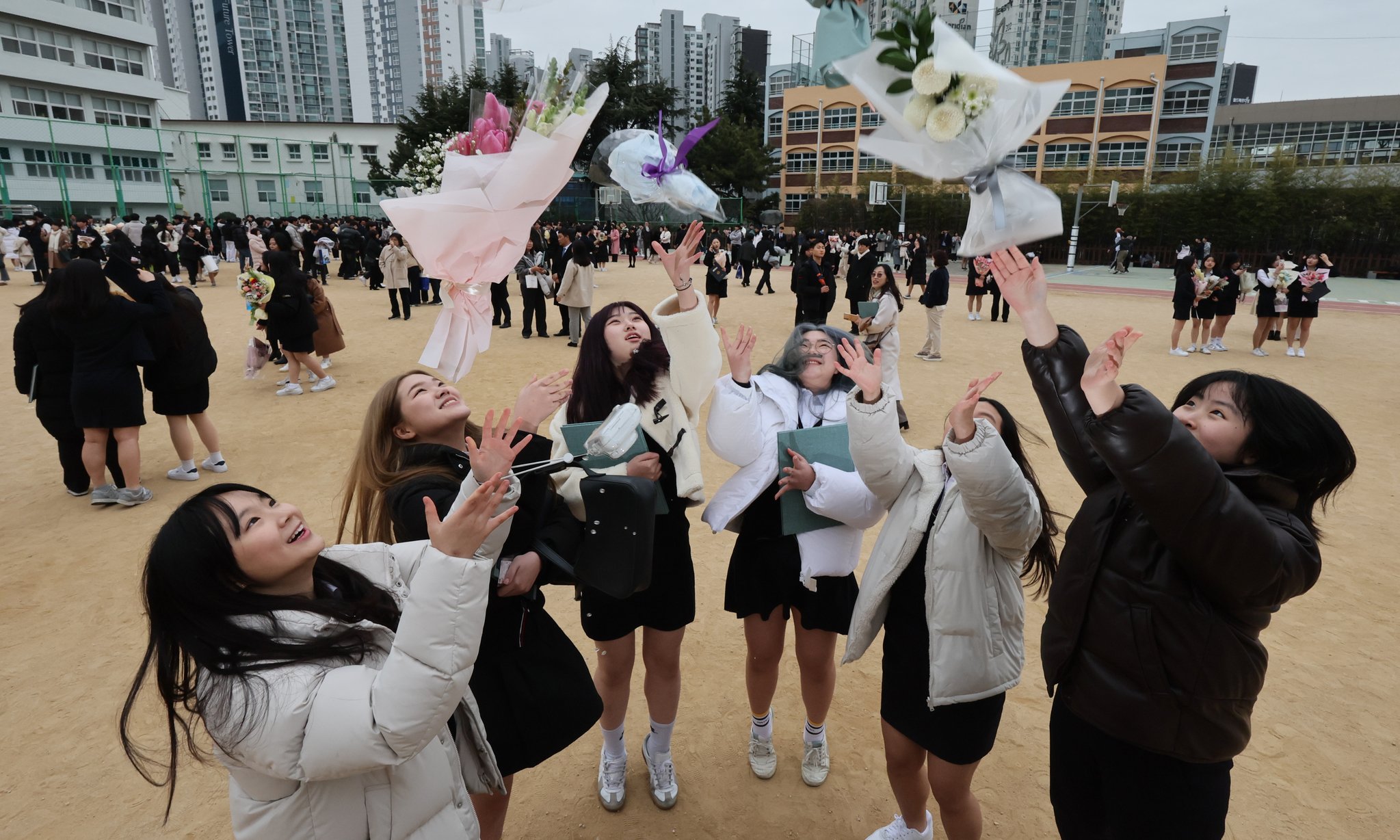 졸업식을 마친 이사벨고 학생들이 운동장에서 꽃다발을 던지며 졸업을 자축하고 있다. 송봉근 기자