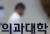 지난 19일 오전 서울의 한 의과대학 출입문으로 관계자가 지나가고 있다.  대한의과대학·의학전문대학원학생협회(의대협)는 정부의 의대 증원 방침에 반발해 동맹 휴학을 결의했다. 뉴스1