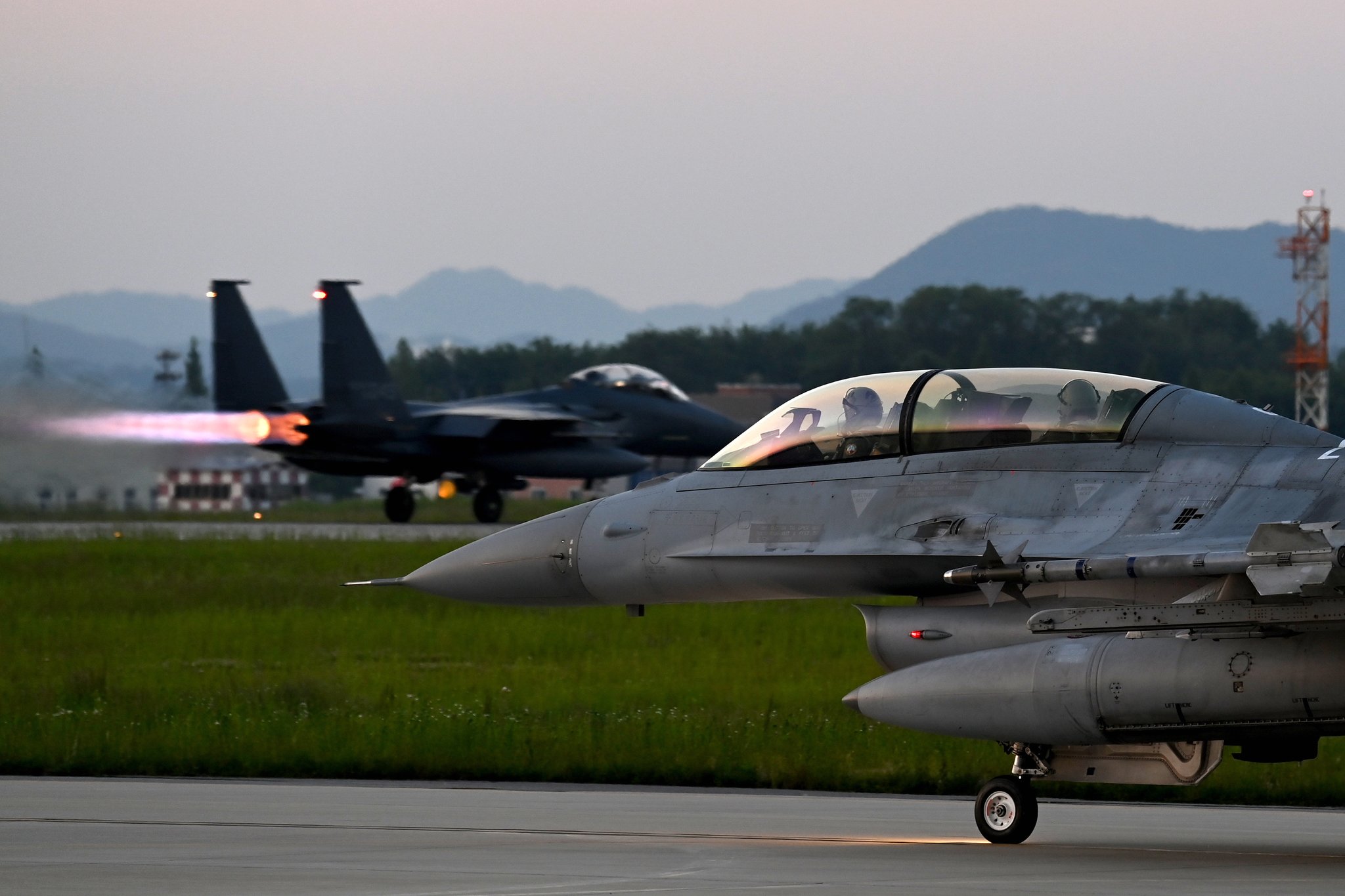 지난 21일 공군 청주기지에서 열린 소링 이글 훈련에서 야간 출격을 위해 이동하는 F-16과 그 뒤로 F-15K가 이륙하기 위해 활주하고 있다. 사진 공군